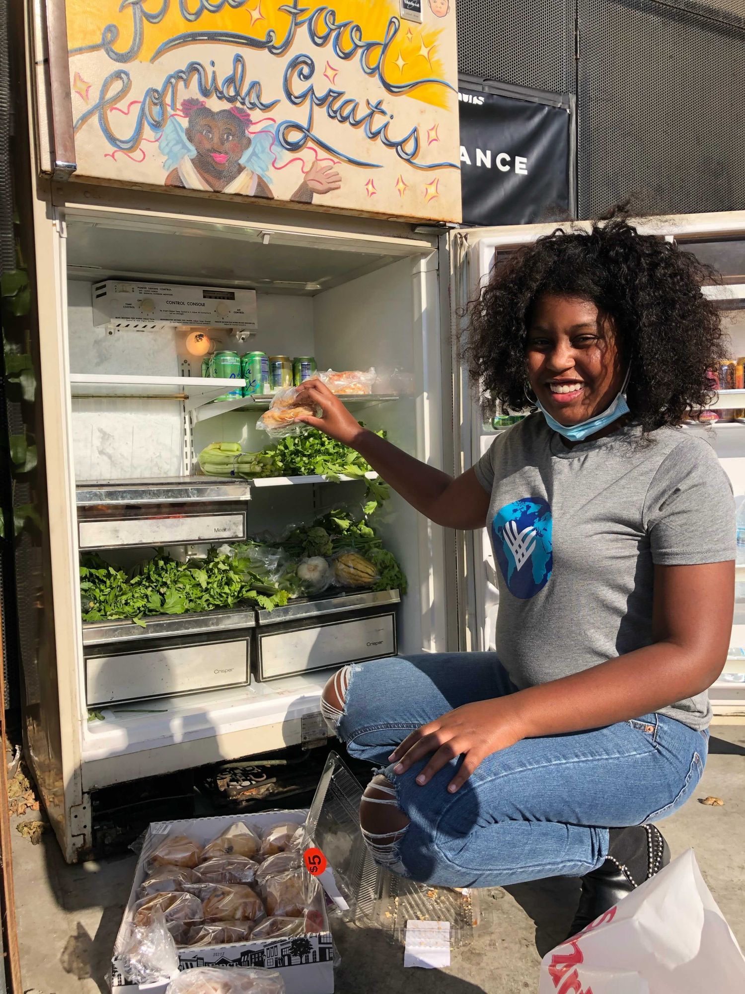 Volunteer stocking a community food fridge with fresh produce; illustrative stock photograph