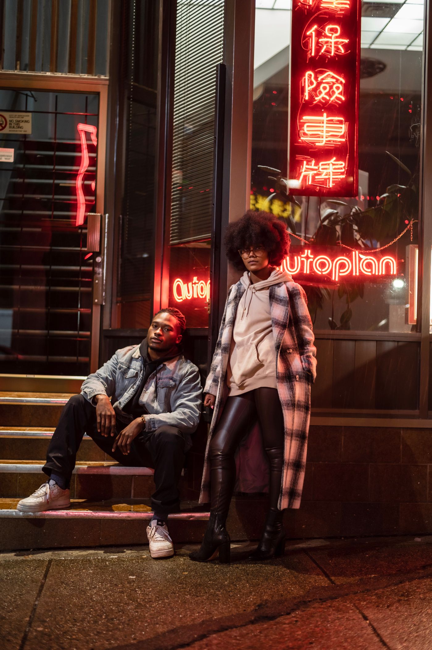 Two friends on a neon-lit city sidewalk at night; illustrative stock photograph